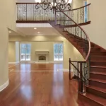 Foyer with balcony and curved staircase by renewstairsca